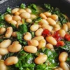 Spinach and white beans power bowl topped with fresh vegetables