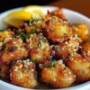 Crispy lemon chicken bites served on a plate with garnished herbs