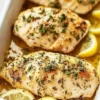 Juicy lemon herb baked chicken breast garnished with fresh herbs.