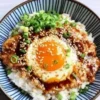 Bowl of Korean Egg Rice topped with a fluffy egg and garnished, ready to serve.