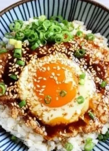 Bowl of Korean Egg Rice topped with a fluffy egg and garnished, ready to serve.