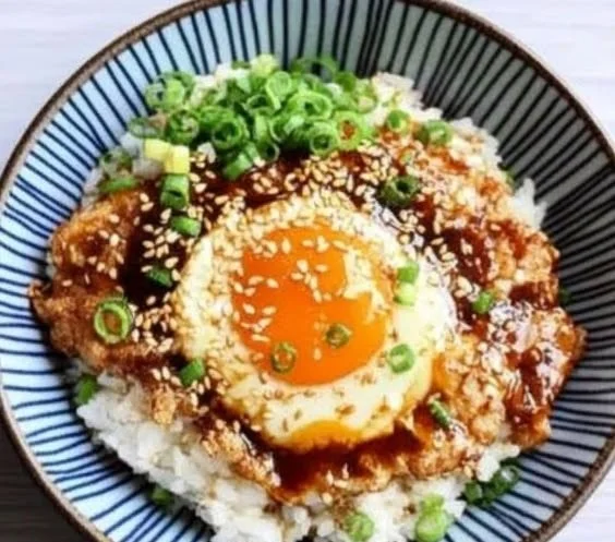 Bowl of Korean Egg Rice topped with a fluffy egg and garnished, ready to serve.