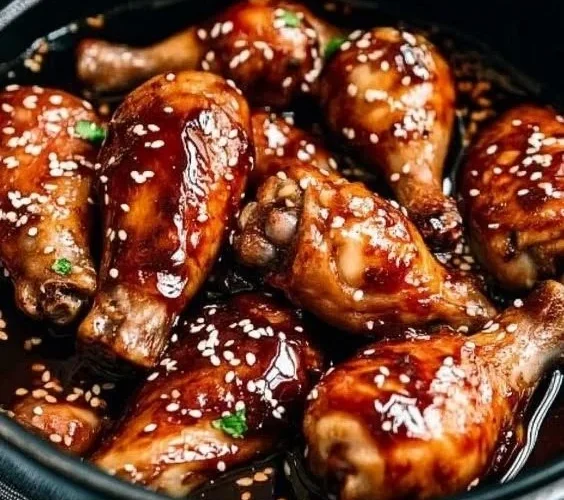 Slow Cooker Asian Glazed Chicken Drumsticks garnished with sesame seeds and herbs