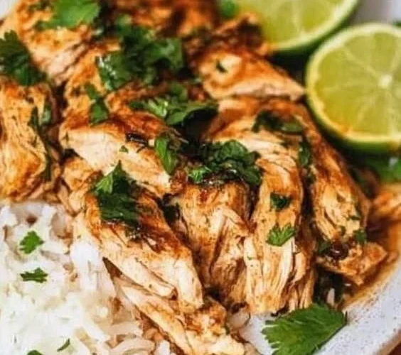 Slow cooker cilantro lime chicken served with fresh lime and cilantro garnish.