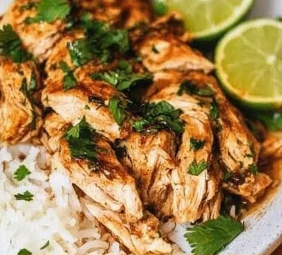 Slow cooker cilantro lime chicken served with fresh lime and cilantro garnish.