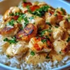 Plate of smothered chicken served over rice with rich gravy and vegetables.