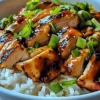 Spicy Maple Chicken served with coconut rice on a white plate, garnished with herbs.