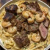 Plate of creamy Steak and Shrimp Alfredo topped with parsley