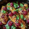 Plate of sweet and spicy jalapeño raspberry chicken garnished with herbs