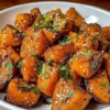 Bowl of sweet and spicy smashed sweet potatoes topped with herbs.
